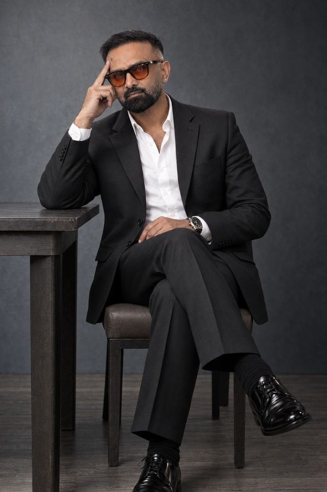 Dr Krish Bharggav, host of The Offer Letter, seated in a black suit in a dark studio