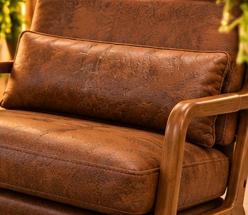 Close-up of a guest armchair’s tan leather cushion and wooden arm